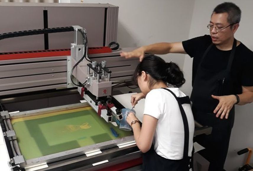 南應大美術系版印中心網版製版與印刷證照培訓班指導學生如何操作全自動網版絹印機